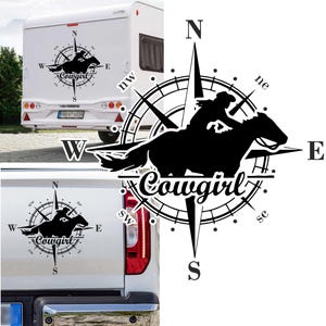 Op de afbeelding: Zwart-witte sticker van een cowgirl die een paard rijdt met een kompasontwerp en het woord "Cowgirl" in een gestileerd lettertype. Het kompas wijst naar het noorden, zuiden, oosten en westen.