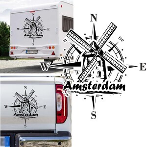 Op de afbeelding: Zwart-wit grafisch ontwerp van een windmolen met een kompas eromheen. De kompaspunten zijn gemarkeerd met N, S, E en W. De tekst "Amsterdam" staat in vetgedrukte, zwarte letters onder de windmolen.