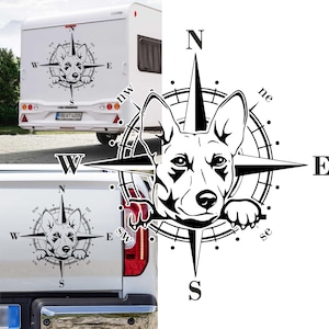 Könnte beinhalten: Schwarzweiß-Illustration eines Hundekopfes in einem Kompass mit den Richtungen Nord, Süd, Ost und West beschriftet. Der Hund schaut direkt auf den Betrachter.