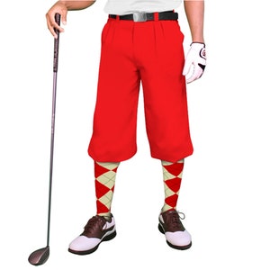 May include: Red golf shorts with a white belt and a pair of red and white argyle socks. The person is holding a golf club.