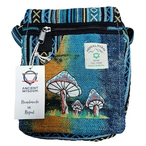 May include: A hemp crossbody bag with a mushroom design. The bag has a zip closure and a tag that says "Ancient Wisdom Handmade in Nepal". The bag is made of blue, green, and orange fabric. It has a "Himalayan Hemp" label.