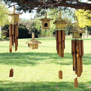 May include: Four bamboo wind chimes and two birdhouses suspended from a tree branch. The wind chimes have pagoda-style roofs made of woven straw. The birdhouses are also made of bamboo and straw, with small openings for birds to enter.