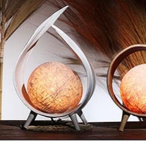May include: Five decorative lamps with white paper shades and wooden bases. The lamps are arranged on a wooden surface with a vase in the centre.