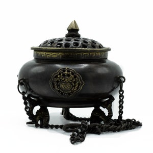 May include: A black metal incense burner with a decorative lid and a chain. The burner has three legs and a floral design on the side.
