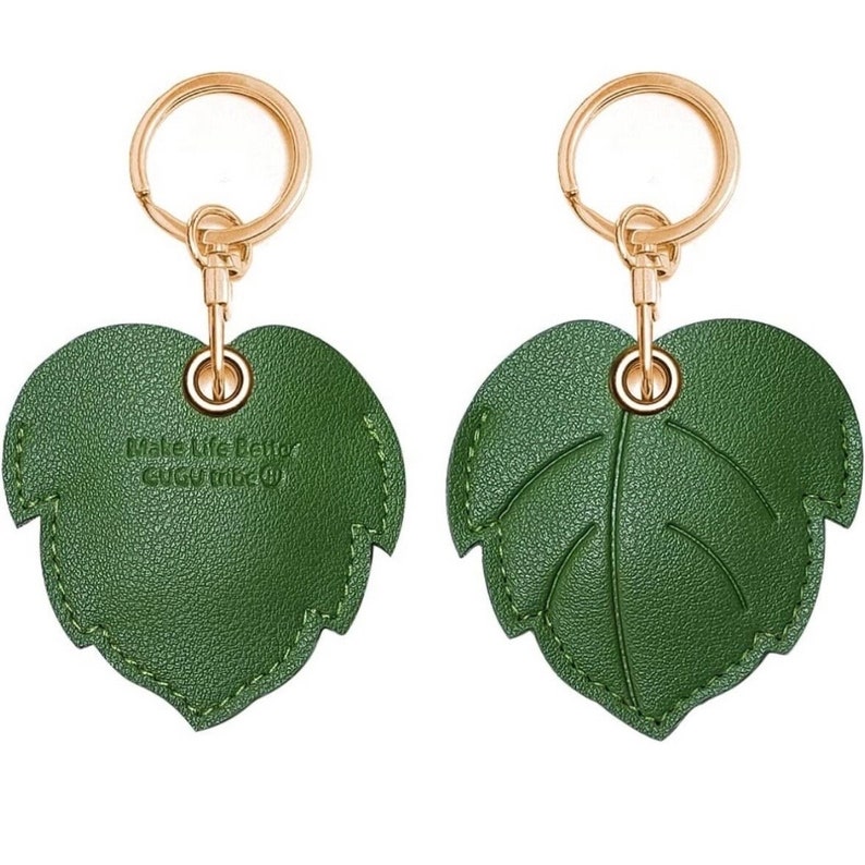 May include: Green leather leaf-shaped keychain with a gold ring and a gold chain. The leaf has a stitched edge and the text "Make Life Better Gucci Tribe" is printed on the back.