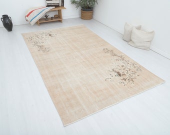 Può includere: Un tappeto beige chiaro con un delicato motivo floreale in marrone. Il tappeto ha un aspetto vissuto, vintage.