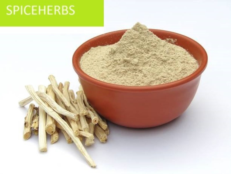 May include: A bowl of light brown powder with a pile of light brown sticks next to it. The bowl is made of terracotta and has a rounded shape. The sticks are thin and have a rough texture. The background is white.