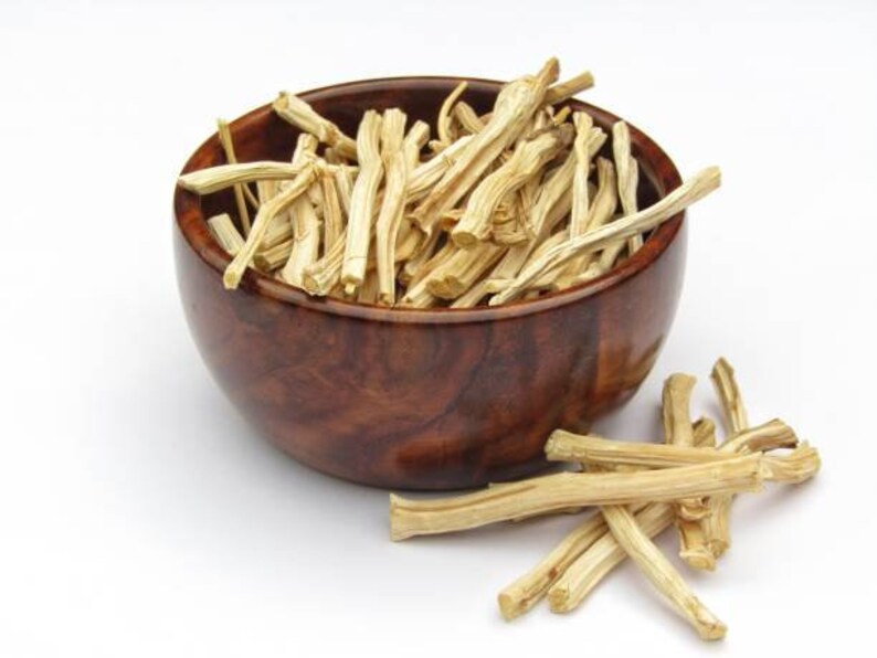 May include: A wooden bowl filled with dried, light brown, thin sticks. Some sticks are scattered on a white surface.