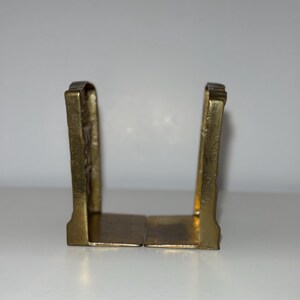 Puede incluir: Dos sujetalibros antiguos de lat&oacute;n. Cada sujetalibros tiene una base rectangular y una parte superior arqueada decorativa. El lat&oacute;n tiene un tono dorado c&aacute;lido, y el dise&ntilde;o parece vintage, agregando un toque de elegancia cl&aacute;sica a cualquier estanter&iacute;a.