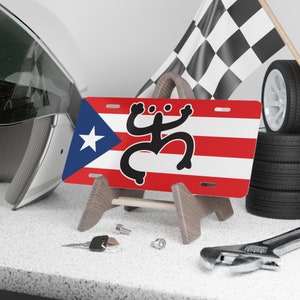 Bandera de Puerto Rico con Coquí Taíno en placa de vanidad negra para auto.