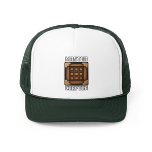 Op de afbeelding: Een witte en groene truckercap met een bruin crafting table-icoon en de tekst "MASTER CRAFTER" op de voorkant.