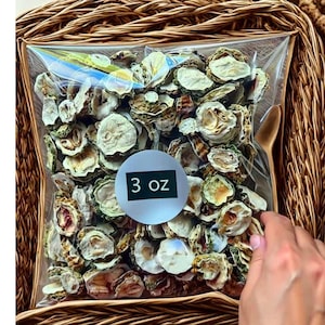 May include: A clear plastic bag filled with dried, light green and brown sliced vegetables. A white sticker with the text "3 oz" is on the bag. The bag is inside a woven basket.