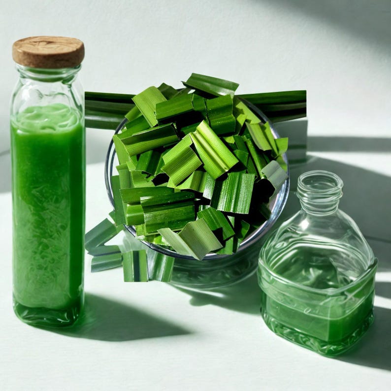 Peut inclure: Une bouteille en verre transparente remplie de liquide vert, surmont&eacute;e d'un bouchon en li&egrave;ge, &agrave; c&ocirc;t&eacute; d'une petite bouteille en verre et d'un bol de feuilles de pandan vertes. Les feuilles sont coup&eacute;es en petits morceaux.