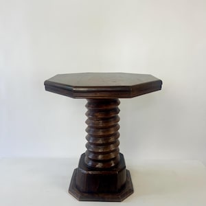 Könnte beinhalten: Ein dunkelbrauner Beistelltisch aus Holz mit einer achteckigen Tischplatte. Die zentrale Stützsäule ist mit einem markanten, spiralförmigen Gewindemuster versehen und ruht auf einem stabilen, passenden achteckigen Sockel.