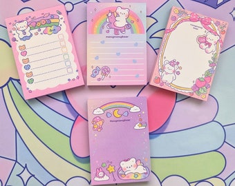 Puede incluir: Cuatro blocs de notas rosas y morados con adorables ositos de dibujos animados y arcoíris. Los blocs de notas tienen diferentes diseños, incluyendo una lista de tareas, un espacio en blanco para escribir y un espacio para notas. Los blocs de notas son perfectos para agregar un toque de fantasía a cualquier escritorio o espacio de trabajo.