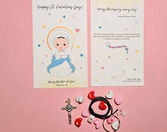 Può includere: Un portachiavi con rosario a forma di cuore rosa e bianco con un ciondolo di rosario blu e bianco. Il portachiavi viene fornito con una carta che dice "Buon San Valentino!" e "Recita il rosario ogni giorno - Maria Madre di Dio".