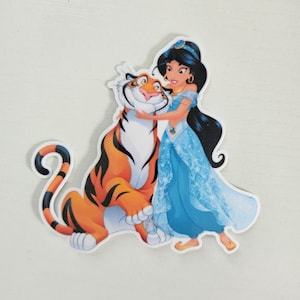 May include: A sticker featuring Princess Jasmine from Aladdin hugging Rajah the tiger. Jasmine is wearing a blue dress and has long black hair. Rajah is orange with black stripes. The sticker is on a white background.