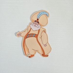 May include: A die-cut sticker featuring a cartoon character in a cream-colored robe and hat. The character has a white beard, orange accents, and a blue feather on the hat. The sticker is likely from a movie or animated series.