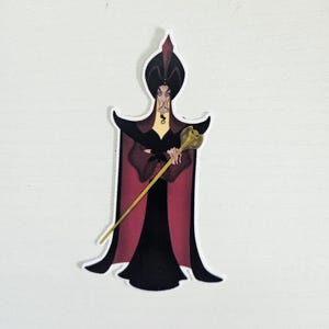 May include: A sticker featuring a cartoon illustration of Jafar from Aladdin. Jafar is depicted in a black and red outfit, holding a golden staff. The sticker has a white border and is set against a white background.