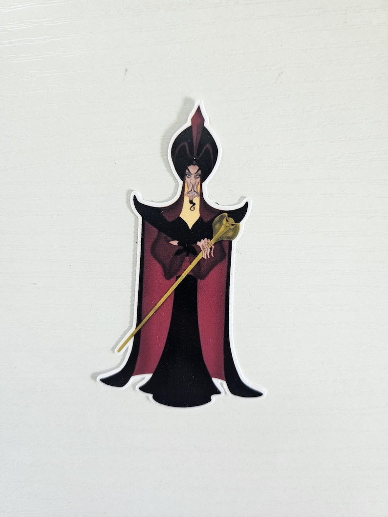 May include: A sticker featuring a cartoon illustration of Jafar from Aladdin. Jafar is depicted in a black and red outfit, holding a golden staff. The sticker has a white border and is set against a white background.
