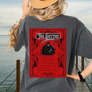 Camisa The Scythe One Dark Window Comfort Color frente e verso, Be Wary Be Clever Be Good e a carta The Scythe nas costas, romance sombrio de Rachel Gillig