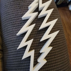 May include: White lightning bolt shaped wall decor. The bolt is made of a thick, rigid material and has a 3D effect.