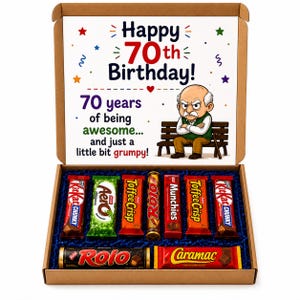 May include: A cardboard gift box containing an assortment of chocolate bars including KitKat Chunky, Aero, Toffee Crisp, Rolo, Munchies, and Caramac. The lid features text reading Happy 70th Birthday and an illustration of a grumpy elderly man.