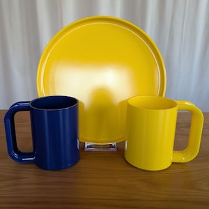May include: A yellow ceramic tray with a blue ceramic mug and a yellow ceramic mug.