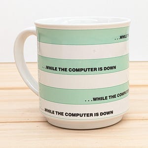 May include: White ceramic mug with green stripes and the text "...WHILE THE COMPUTER IS DOWN" repeated on each stripe.