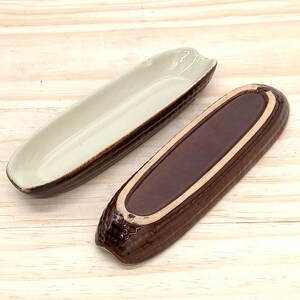 Peut inclure: Deux plats de service en céramique en forme d'épi de maïs. L'un est beige clair à l'intérieur avec un bord et un extérieur marron. L'autre est marron à l'intérieur et à l'extérieur, avec un bord beige. Sur une surface en bois clair.