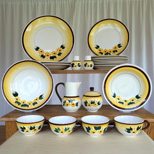 Puede incluir: Un juego de vajilla de cerámica vintage con estampado floral amarillo y marrón, que incluye platos, cuencos, una jarra de crema, un azucarero y tazas de té.