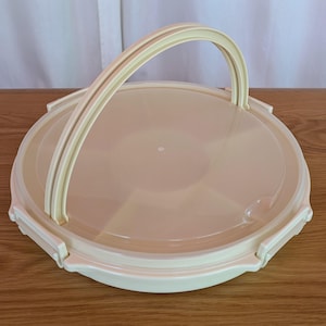 以下が含まれることがあります： 蓋とハンドルが付いたベージュのプラスチック製のサービングトレイ。トレイには、スナックやアペタイザーを入れるための複数のコンパートメントがあります。