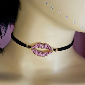 May include: A black choker necklace with a pink rhinestone lip charm.