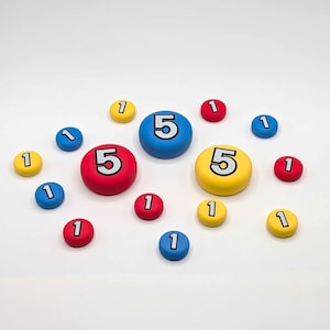 Peut inclure: Un ensemble de jetons de jeu ronds et colorés en rouge, bleu et jaune. Deux grands jetons portent le chiffre 5 en noir, tandis que onze jetons plus petits portent le chiffre 1 en noir. Les jetons ont une finition mate lisse et des bords arrondis.