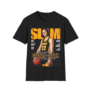 May include: Black t-shirt featuring a magazine cover with a basketball player holding a basketball. The magazine cover reads "SLAM" and "THE LEGEND OF CAITLIN CLARK IS JUST BEGINNING".