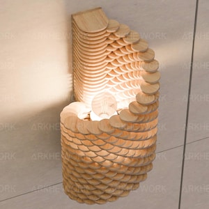 Puede incluir: Una l&aacute;mpara de pared de madera con un dise&ntilde;o &uacute;nico hecho de c&iacute;rculos apilados y superpuestos. La l&aacute;mpara est&aacute; iluminada por una bombilla dentro del centro de los c&iacute;rculos.