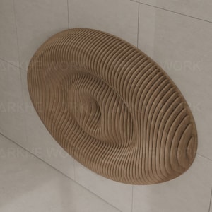 May include: A large, oval-shaped wall sculpture made of wood with a wavy, rippled pattern. The sculpture is light brown in color and has a 3D effect.