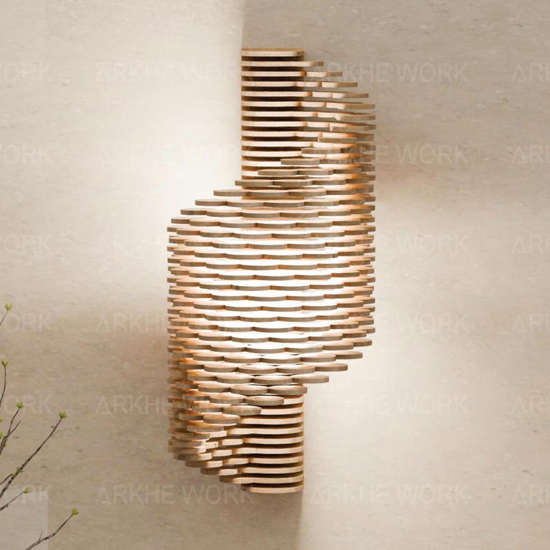 Puede incluir: Una l&aacute;mpara de pared de madera con un dise&ntilde;o geom&eacute;trico. La l&aacute;mpara est&aacute; hecha de finas piezas de madera apiladas que crean un aspecto &uacute;nico y moderno. La luz brilla a trav&eacute;s de los huecos en la madera, creando un brillo c&aacute;lido y acogedor.