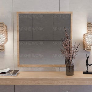 Puede incluir: Una consola de madera con un espejo encima. La consola tiene un acabado de madera clara y un estante. El espejo es rectangular y tiene un marco de madera. Hay dos apliques de pared a cada lado del espejo. Los apliques son de madera y tienen un dise&ntilde;o geom&eacute;trico. Hay un jarr&oacute;n con flores rosas en la consola. Hay una peque&ntilde;a escultura de una persona en la consola.