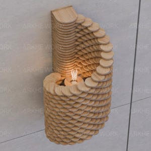 Puede incluir: Una l&aacute;mpara de pared de madera con un dise&ntilde;o en espiral. La l&aacute;mpara tiene una bombilla en el centro y est&aacute; hecha de muchas piezas peque&ntilde;as de madera superpuestas.