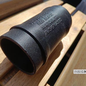 May include: A black, cylindrical automotive part with a textured finish. The surface features embossed text reading VOLVO 240/740 RED BLOCK MAF DELETE INSIGNIAS3D. The object has a hollow interior and a stepped design on one end.