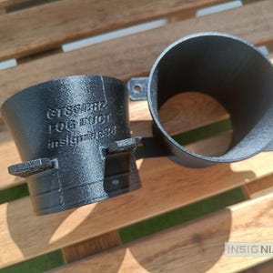 May include: Two black, cylindrical, 3D-printed automotive fog ducts featuring mounting tabs and textured surfaces. The side of one duct is embossed with the text GTS647RZ, FOG DUCT, and insignias3d. The components have a hollow, open-ended design.