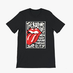 May include: Black t-shirt featuring a white and red graphic of the Rolling Stones' iconic tongue and lips logo. The graphic includes text that reads "The Rolling Stones at New Haven Arena Thursday June 18, 19, 20".