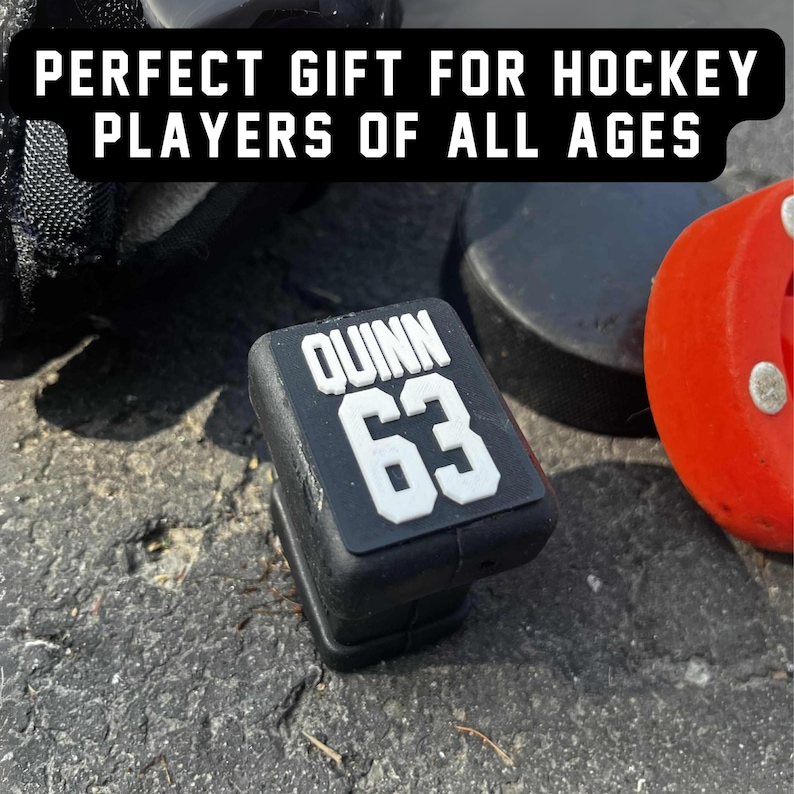 Custom hockey stick end cap topper personalized with player name and number, displayed with hockey equipment, gift idea for players.