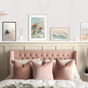 May include: A bedroom scene featuring a pink tufted headboard, matching pillows, and framed beach-themed art. The art includes images of sea turtles, waves, and a beach scene. Decorative vases and a small plant add to the room's aesthetic.