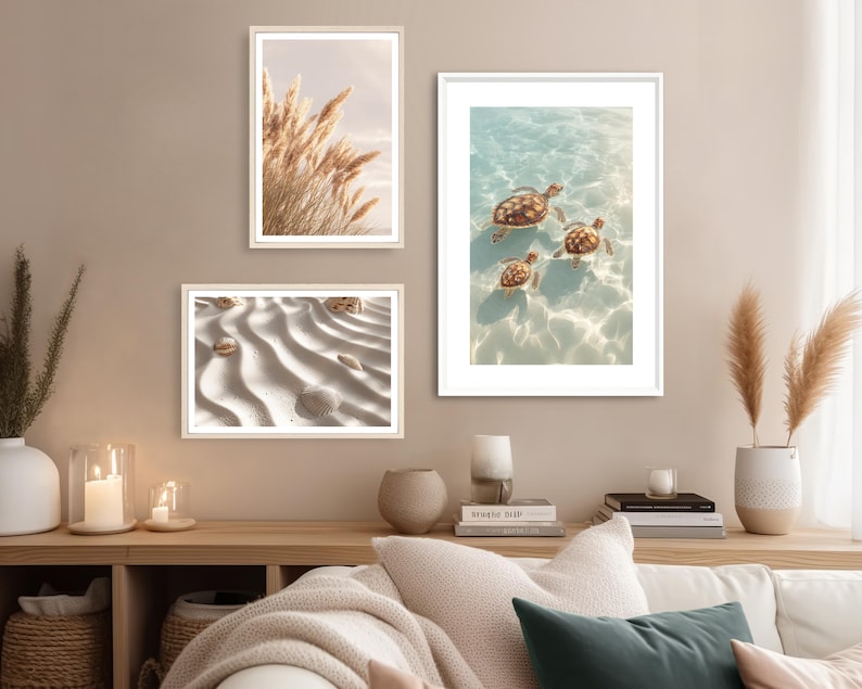 May include: Three framed art prints featuring nature scenes. One print shows pampas grass against a soft sky. Another depicts three sea turtles swimming in clear water. The third print displays seashells on rippled sand.