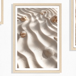 Op de afbeelding: Een ingelijste print met een close-up van geribbeld zand met verspreide schelpen. Het zand is lichtbeige van kleur en de schelpen variëren in grootte en textuur, met tinten bruin en wit. Het kunstwerk zit in een licht houten frame.