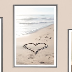 Peut inclure: Impression encadrée d'une scène de plage avec un cœur dessiné dans le sable. L'image montre une plage de sable avec de douces vagues et des empreintes de pas menant à l'eau. Le cœur est le point central, évoquant l'amour et la tranquillité.