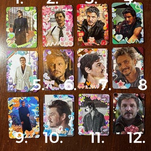May include: Twelve colourful cards featuring different images of a man. Each card has a number on it, from 1 to 12. The cards are decorated with stickers and glitter.