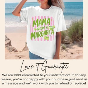 May include: White t-shirt with the text "MAMA NEEDS A MARGARITA" in green and pink. The design includes a margarita glass and lime slices. The shirt is worn by a person on a beach.